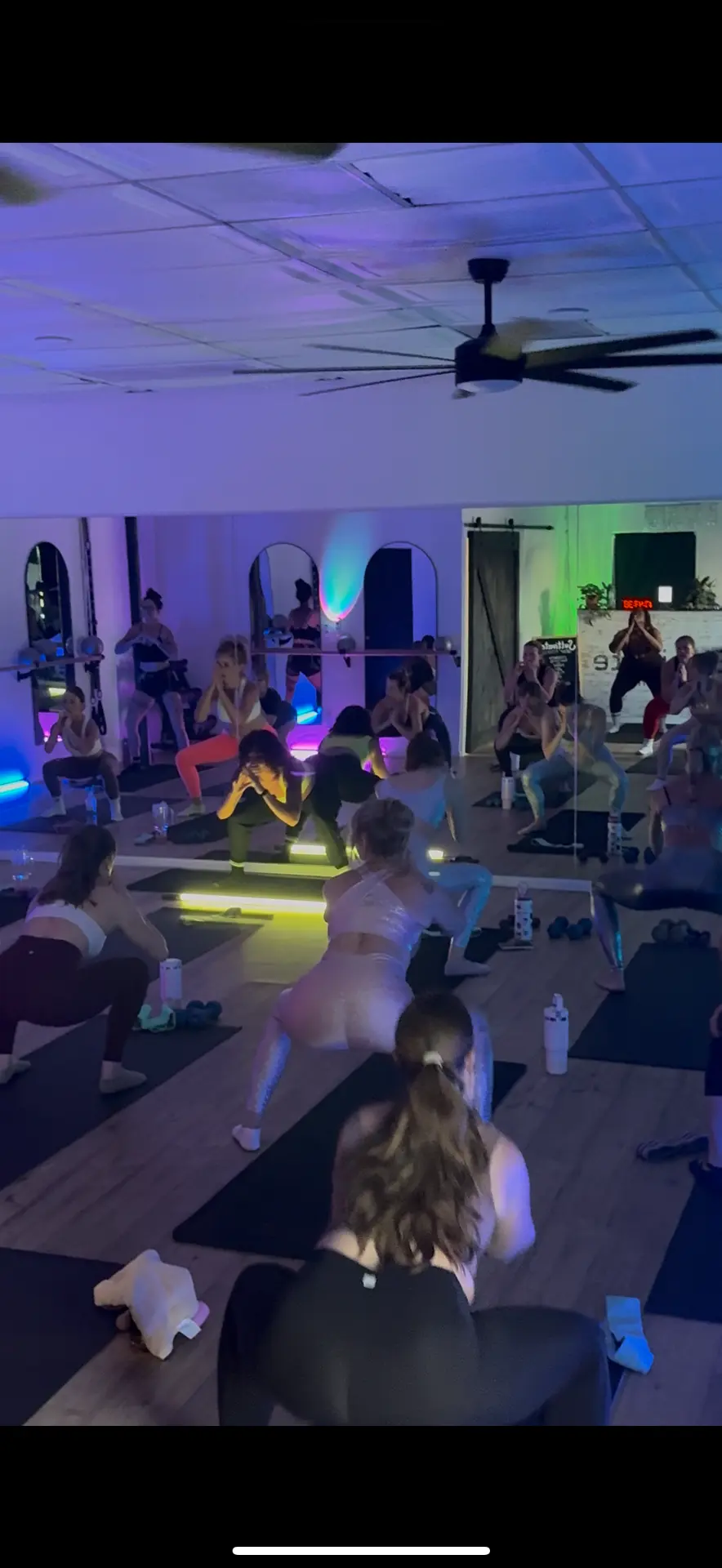 Group holding a wide squat in neon haze